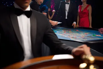 A professional dealer in a tuxedo greeting players at the roulette table, symbolizing the authentic live casino feel at MALIWIN.