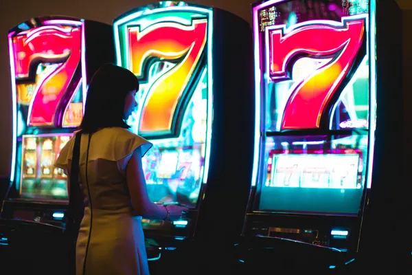 A woman smiling while playing online games on her laptop, surrounded by neon casino elements, showcasing MALIWIN’s diverse game collection.