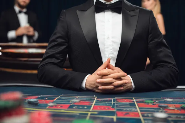A woman in a luxurious green gown next to an ornate roulette wheel, capturing the upscale casino mood of MALIWIN.